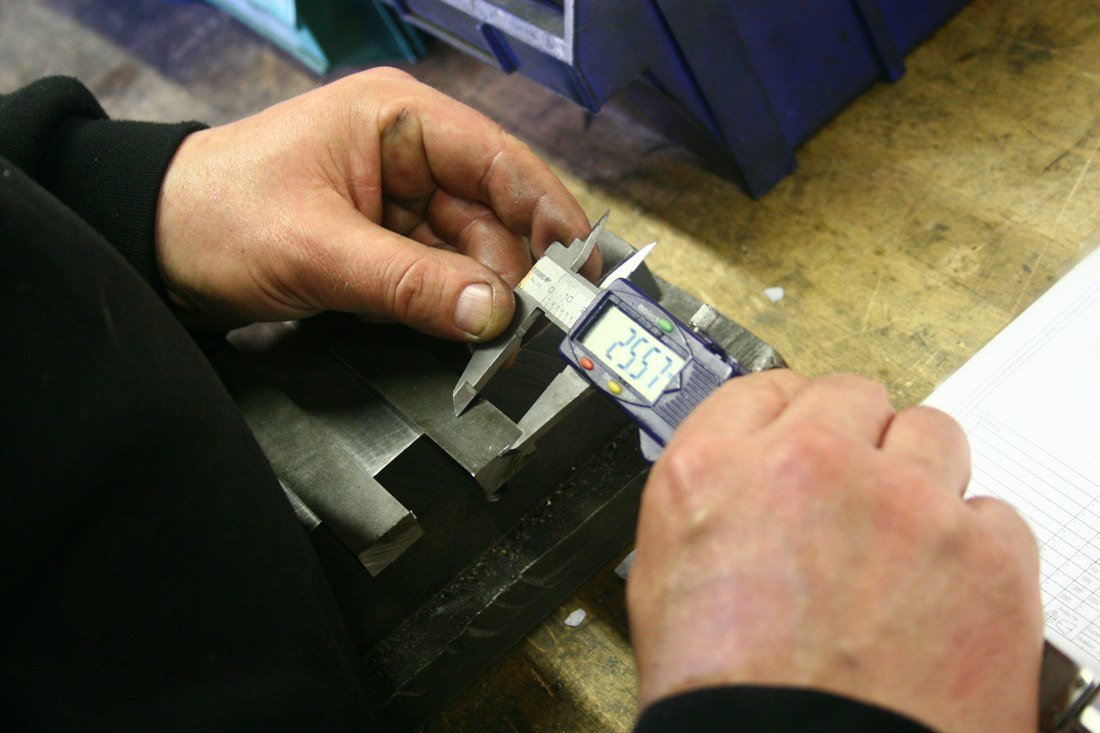 Digital caliper measuring a metal part (demonstration image)
